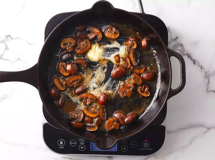 Butter is added to the skillet with mushrooms.