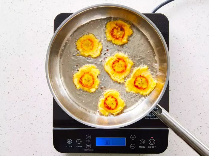 A pan with tostones frying in hot oil.