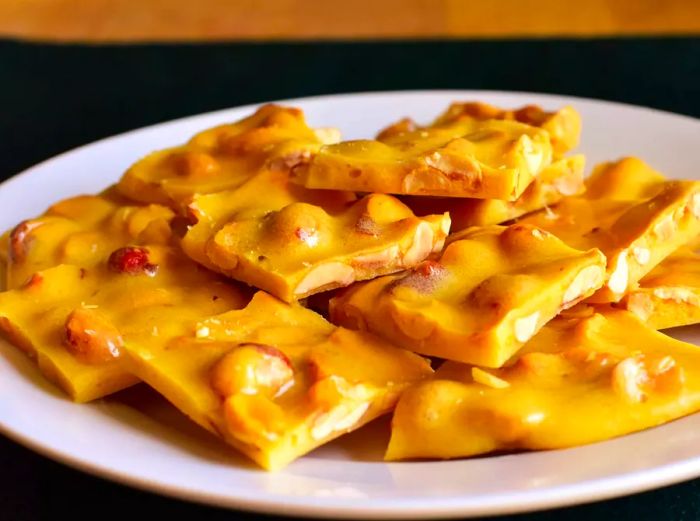 A plate of crunchy, golden-brown peanut brittle pieces