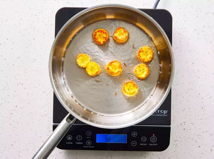 A skillet filled with golden-brown plantain slices.