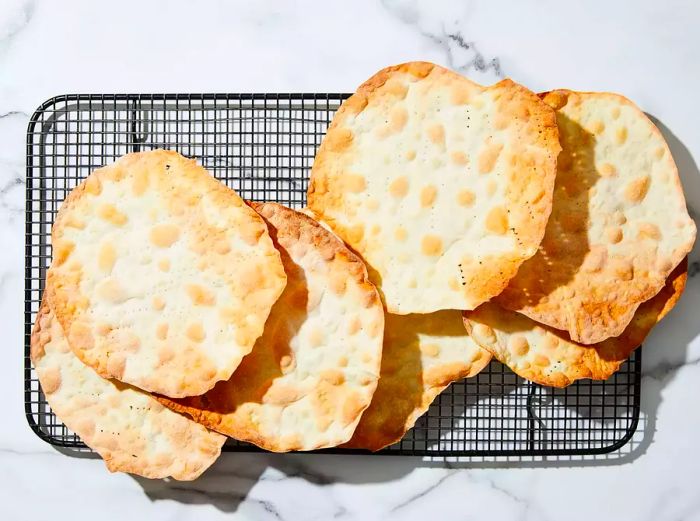 A top-down view of baked matzah resting on a wire rack.