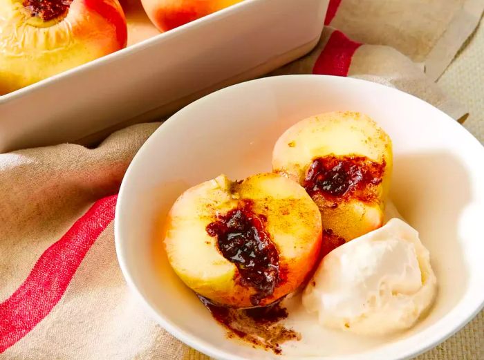 A close-up of a baked apple, halved and served with a scoop of vanilla ice cream