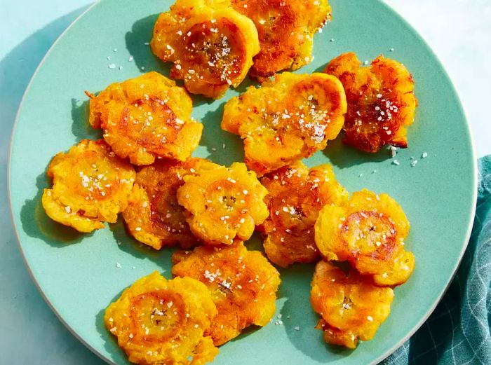 A plate of Puerto Rican tostones garnished with a sprinkle of flaky salt.