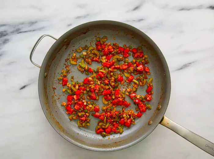 Onions, bell peppers, and celery softening in hot butter.