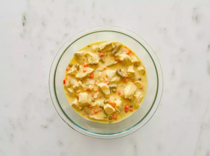 Bird's-eye view of the chicken, vegetables, condensed soup, and milk in a bowl.