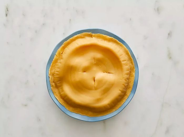 Bird's-eye view of a pot pie with a top crust, featuring four slits cut into it.