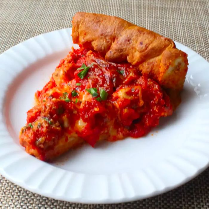 Close-up shot of a slice of Chicago Deep-Dish Pizza served on a white plate