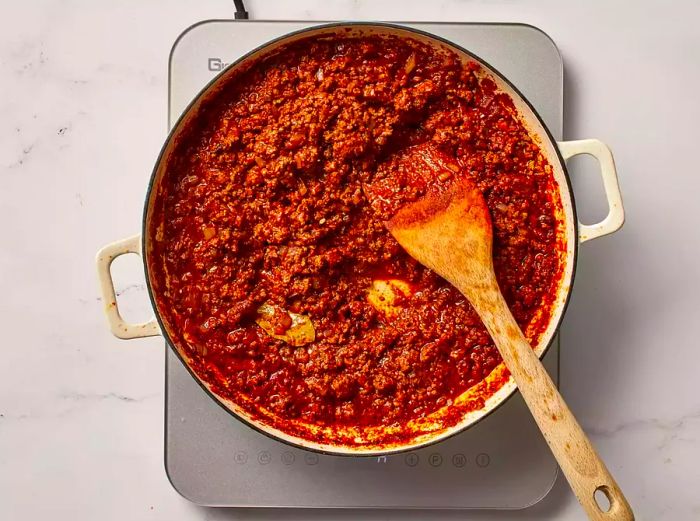 Cincinnati chili simmering in a skillet on the stove.