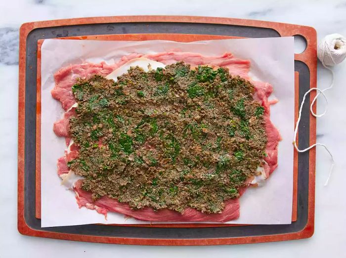 The mushroom and spinach mixture is spread evenly over the prosciutto layer.