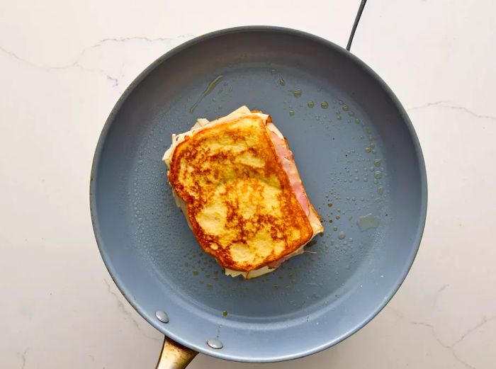 A Monte Cristo sandwich frying in a skillet.