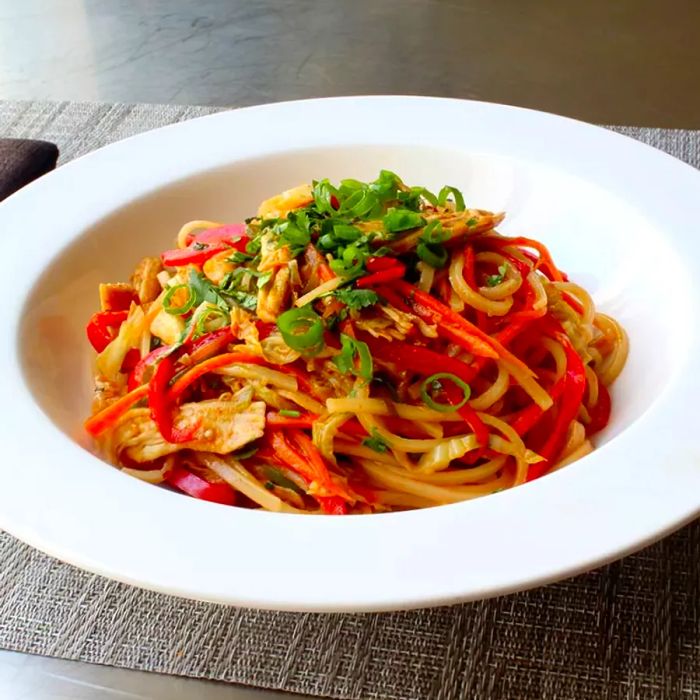 Close-up shot of Spicy Chicken Noodles served in a white bowl