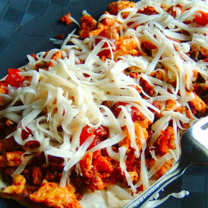 Close-up view of a plate of Authentic Mexican Breakfast Tacos with melted cheese, served with a fork.