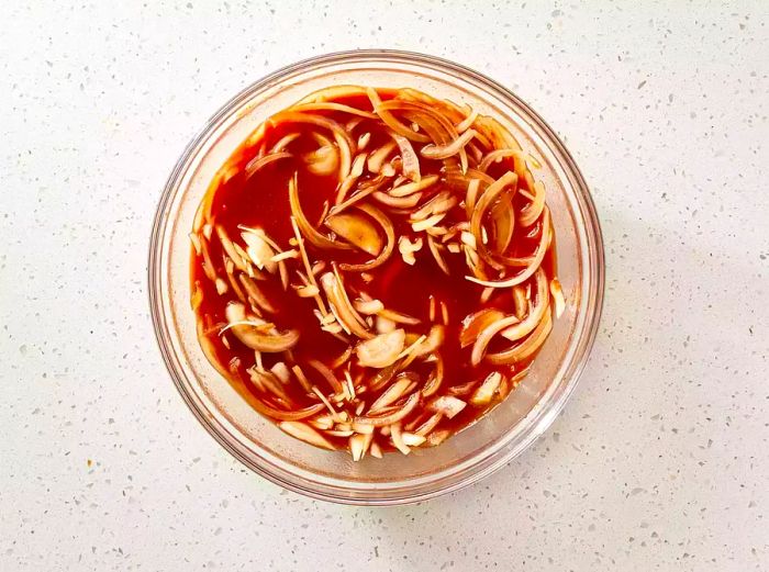 BBQ sauce with onions in a glass mixing bowl