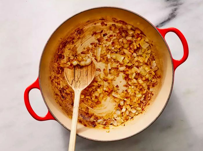 Bird's eye view of onions and garlic sautéing in a pan.