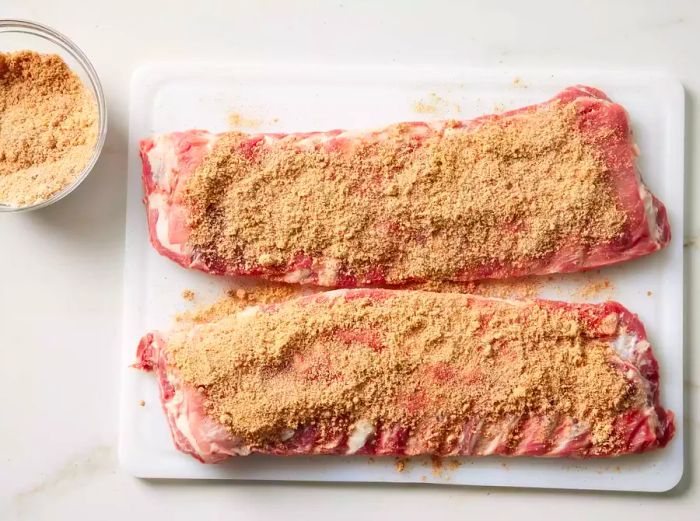 Two racks of pork spare ribs coated with brown sugar and seasoning.