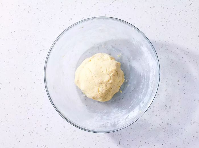 A ball of Ricotta Gnocchi dough in a glass bowl