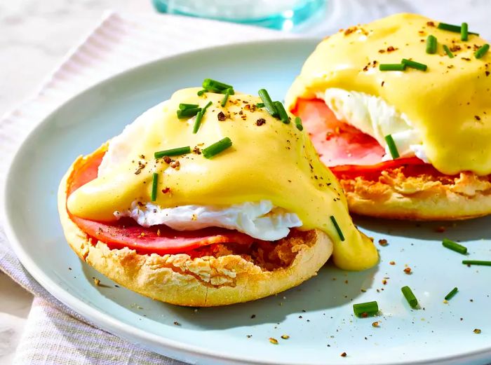 A high-angle shot of two eggs Benedict served on a blue plate.