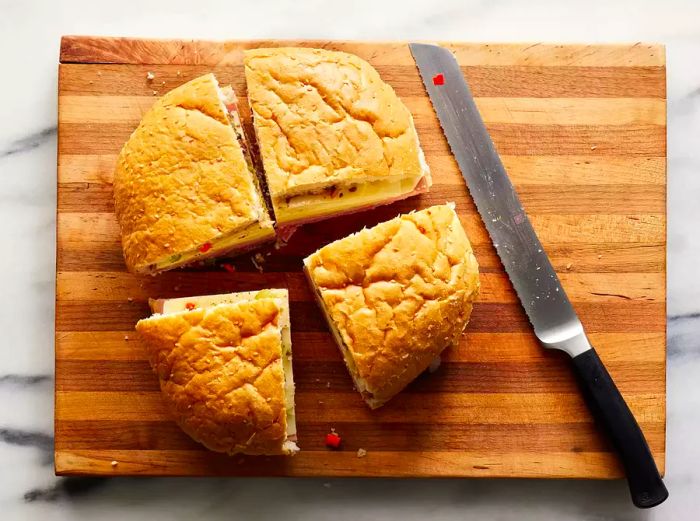 A top-down view of a sandwich on a cutting board, cut into quarters.