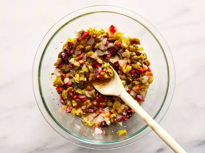 An overhead view of the olive salad mixture in a glass bowl.