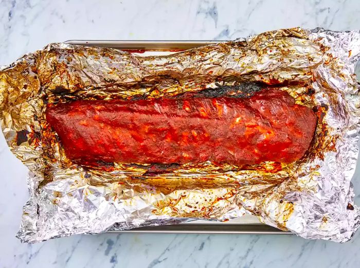 Cooked rack of ribs wrapped in aluminum foil