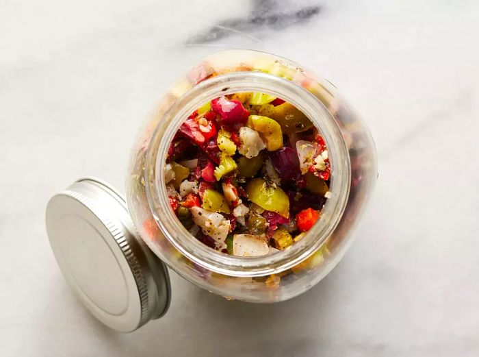 A top-down view of an olive salad mixture in a mason jar.