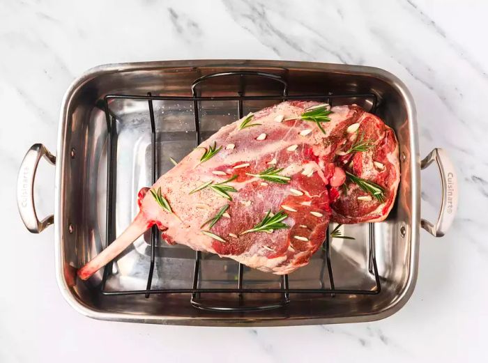 Roast leg of lamb prepared with rosemary, placed on a rack.