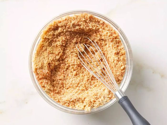 A bowl of brown sugar, fajita seasoning, and paprika being blended together.