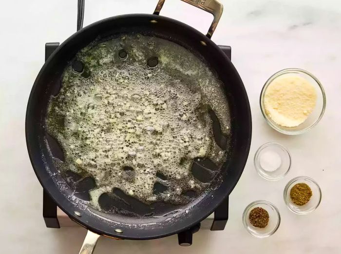 Garlic sizzling in melted butter, turning soft and golden in the skillet.