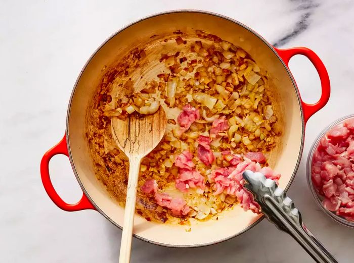 Bird's eye view of onions, garlic, and pork cooking together in a pan.