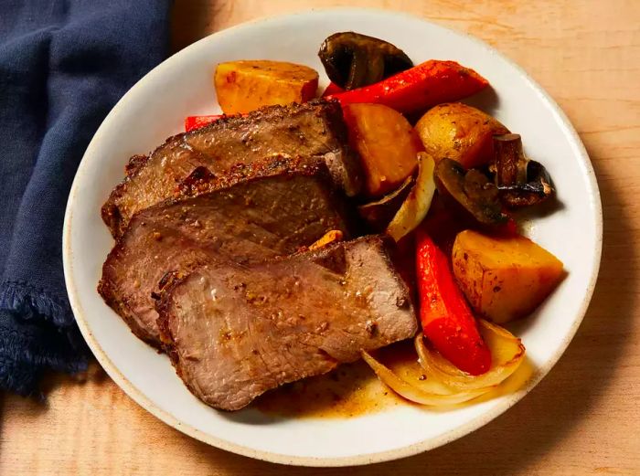 Top Sirloin Roast served with potatoes, carrots, onions, and mushrooms on a plate