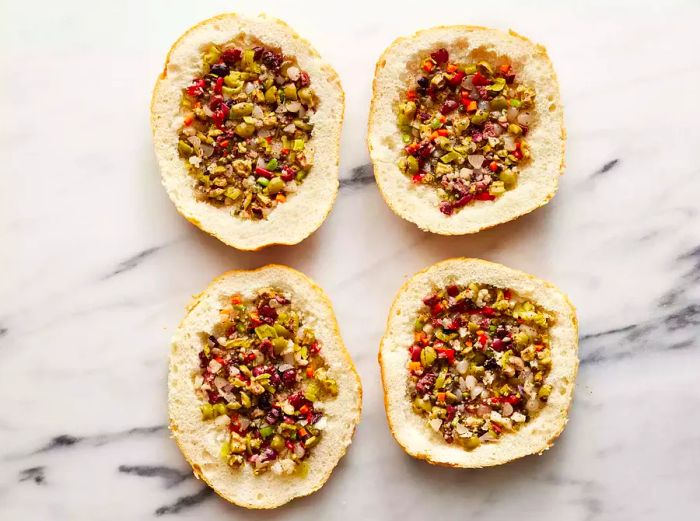 A top-down view of slices of bread generously filled with the olive salad mixture.