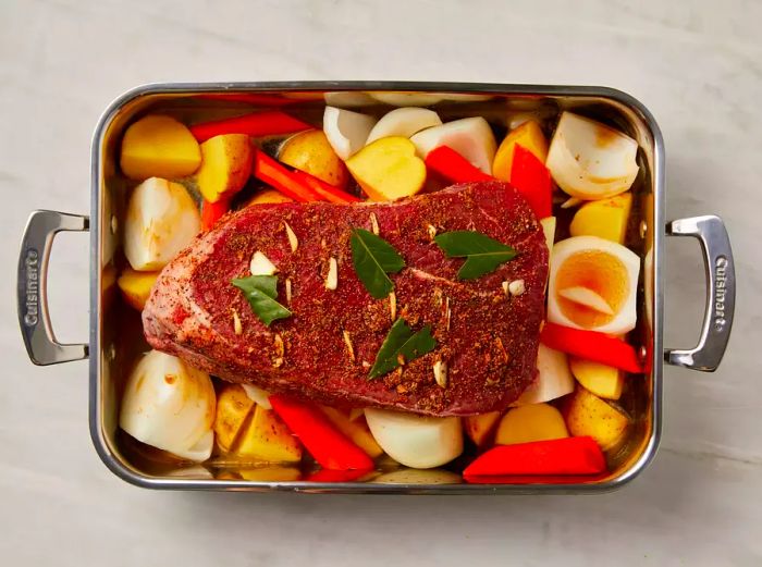 Roasting pan with carrots, onions, potatoes, and a top sirloin roast placed on top