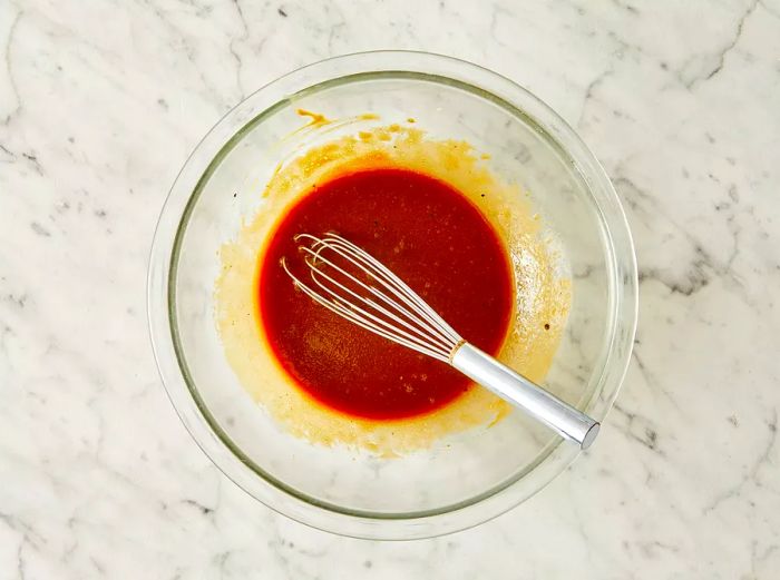 In a bowl, combine olive oil, soy sauce, garlic, mustard, salt, and pepper by whisking them together.