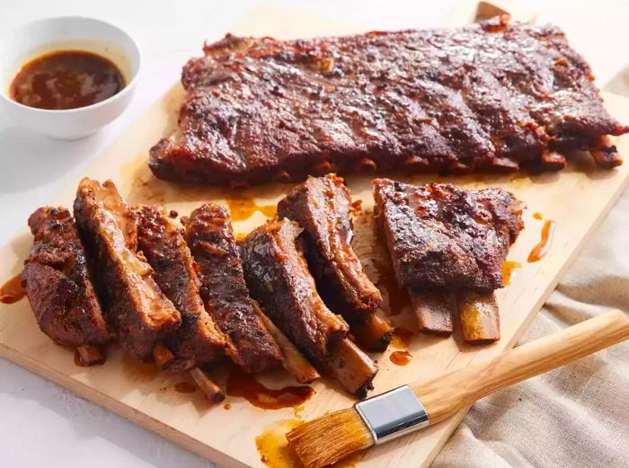 A cutting board with two racks of perfectly cooked pork spare ribs.