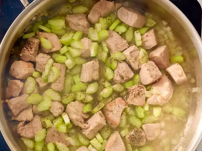 Onions, celery, hot water, and seasonings are now added to the skillet.