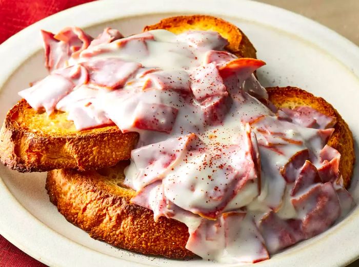 A plate with two slices of toast, each topped with a generous portion of creamed chipped beef