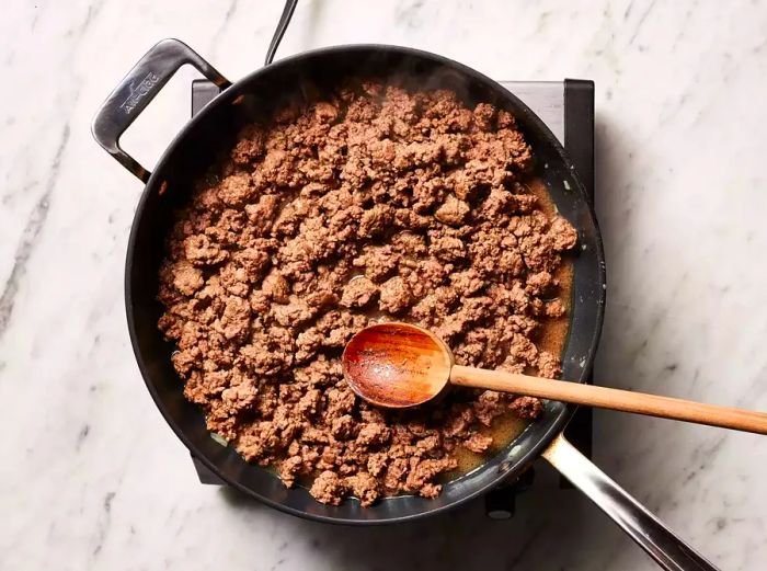 Ground beef browning and crumbling in the skillet.