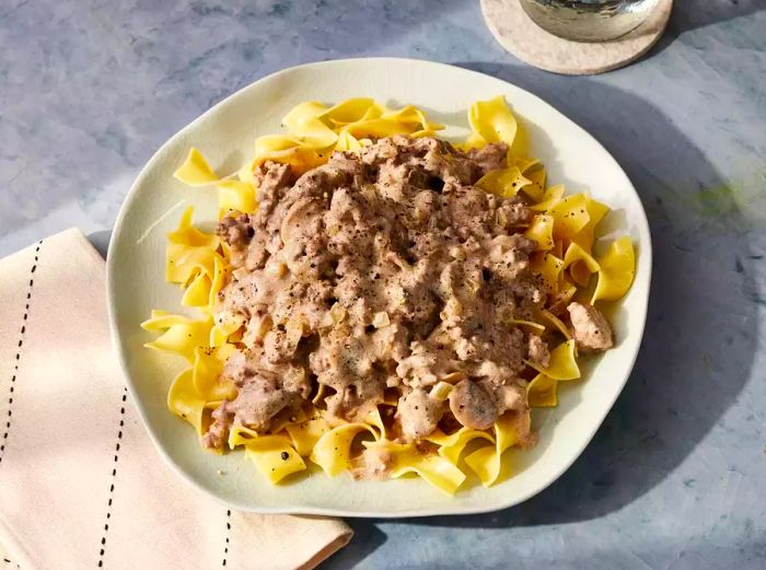 Aerial view of a plate of egg noodles, crowned with beef stroganoff.