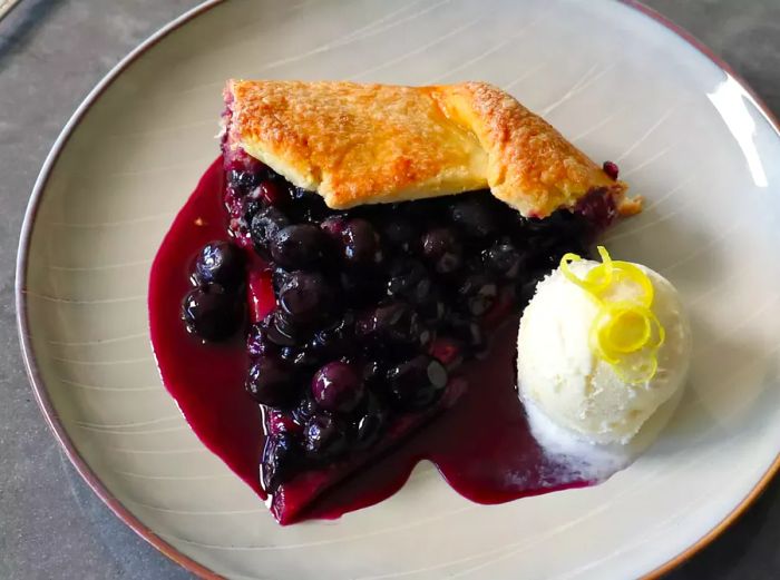 A slice of blueberry tart served with a side of ice cream