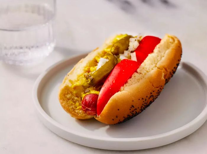 A mid-angle view of a Chicago-style hot dog served on a white plate.