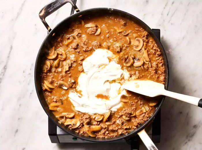 Mushrooms and onions stirred into the skillet, along with sour cream, until the sauce is heated.