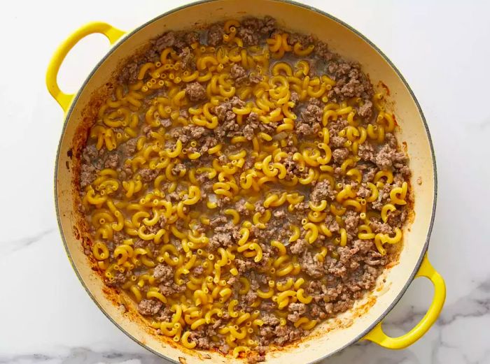 Water added to the ground beef and macaroni mixture in the skillet