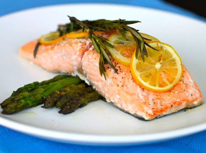 Close-up view of Lemon Rosemary Salmon served over asparagus on a white plate.