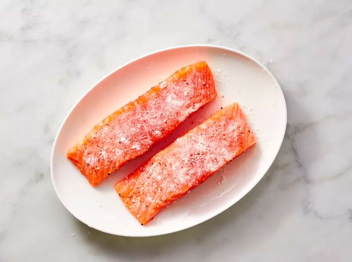 Raw salmon steaks seasoned and served on a white plate.