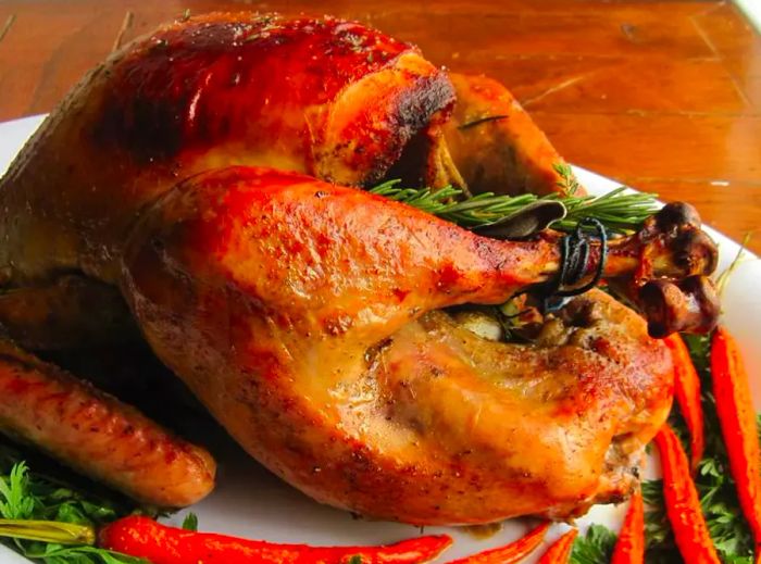 A beautifully roasted turkey surrounded by vegetables on a serving platter