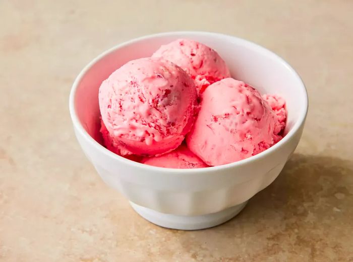 Gazing at a bowl filled with creamy, eggless strawberry ice cream scoops.