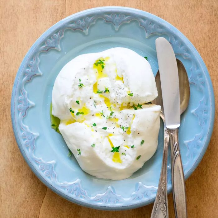 Apulian burrata cheese drizzled with olive oil, sprinkled with thyme, salt, and pepper.