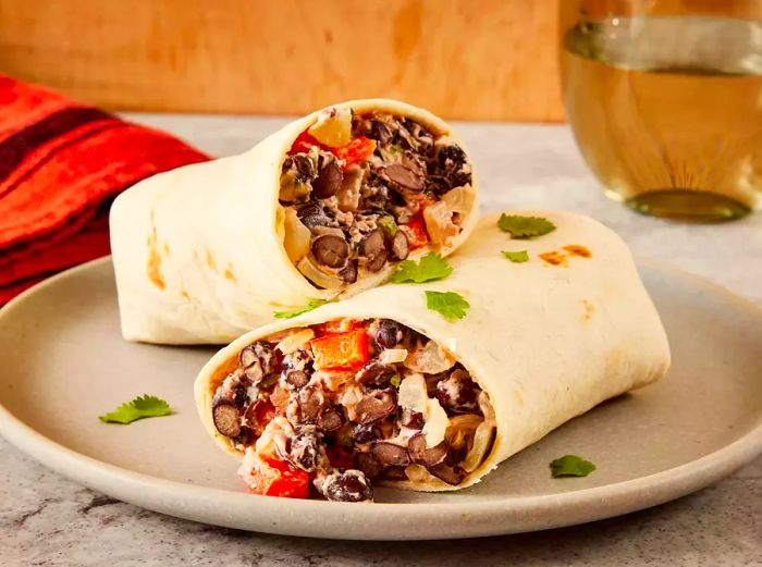 A close-up shot of two black bean burritos stacked together