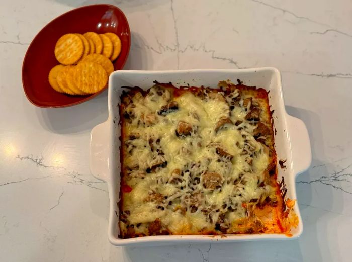 Pizza dip served in a casserole dish with crackers on the side