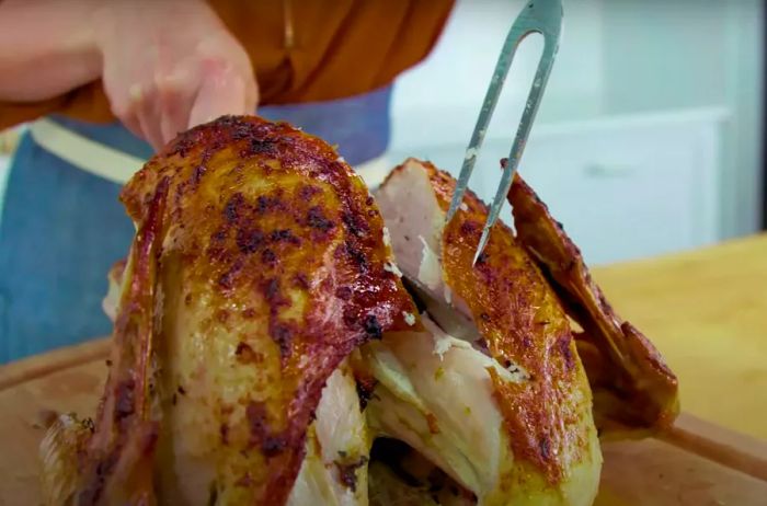 Carving the breast from the turkey using a sharp knife and fork.